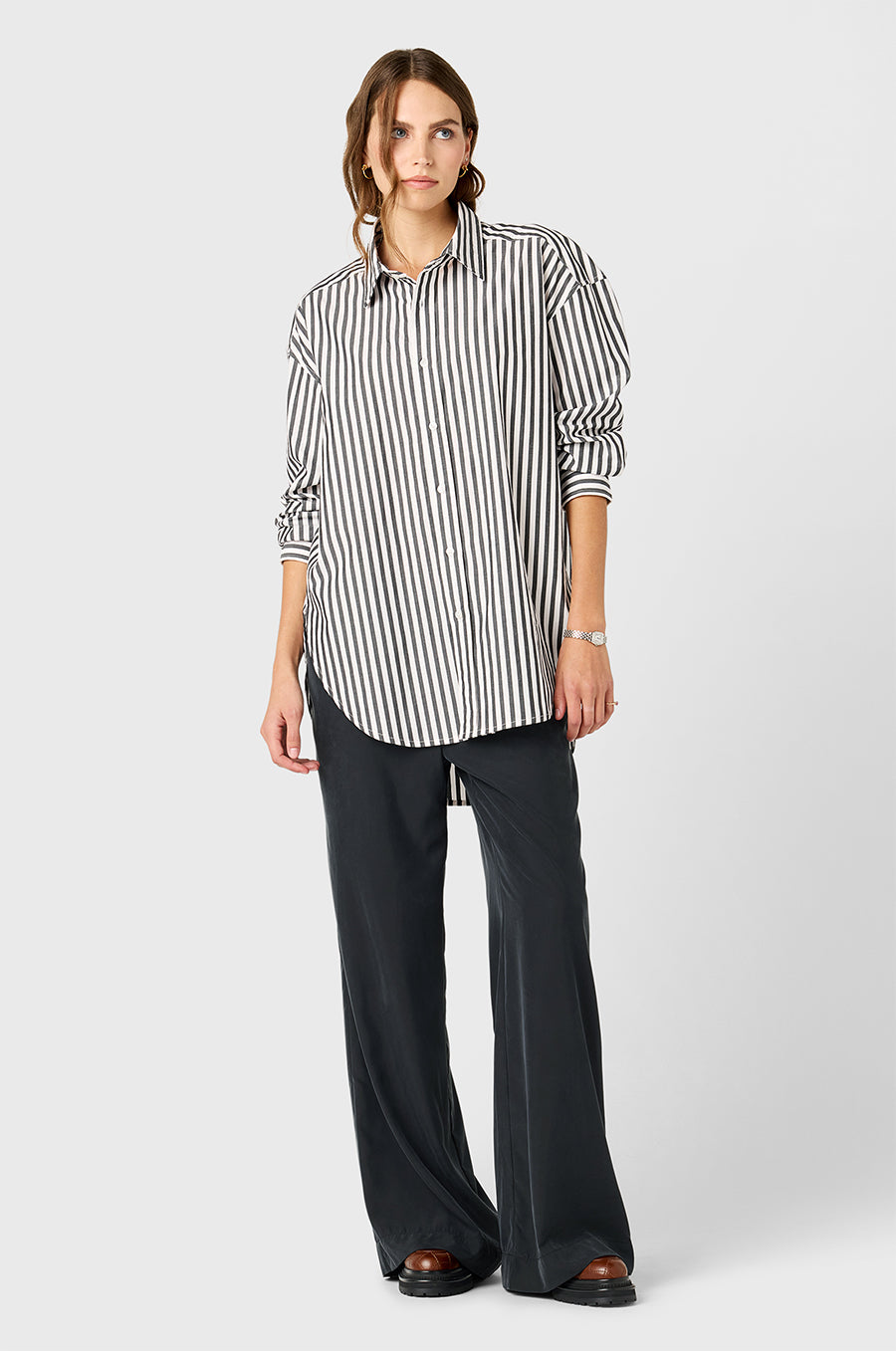 Model wearing The Lady & The Sailor Curved Hem Button up in Black/Ivory Stripe and Silky Wide Leg Pant in Washed Black.