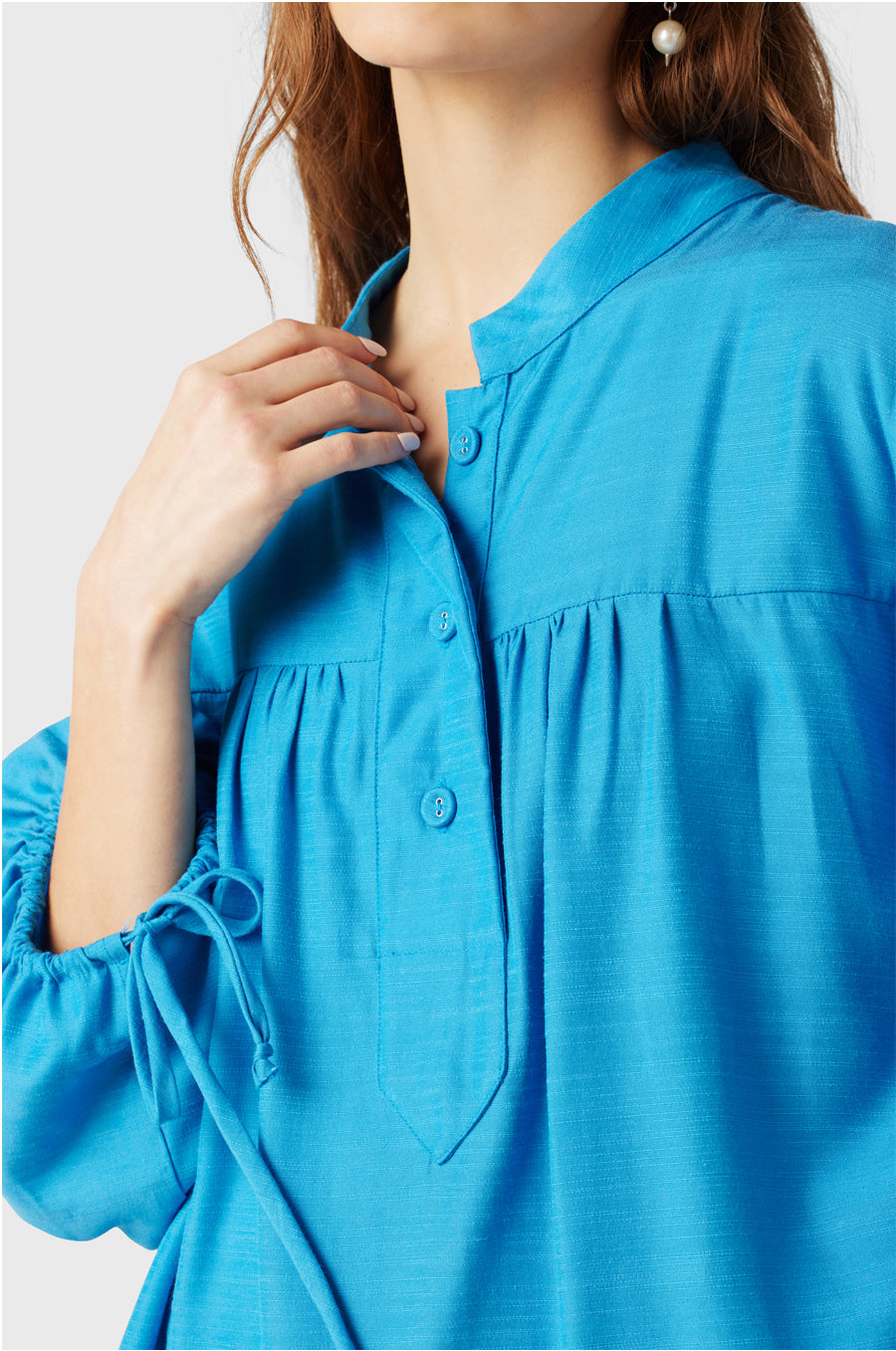 Brunette Model wearing the lady & the sailor Billow Sleeve Mini Dress in Turquoise.