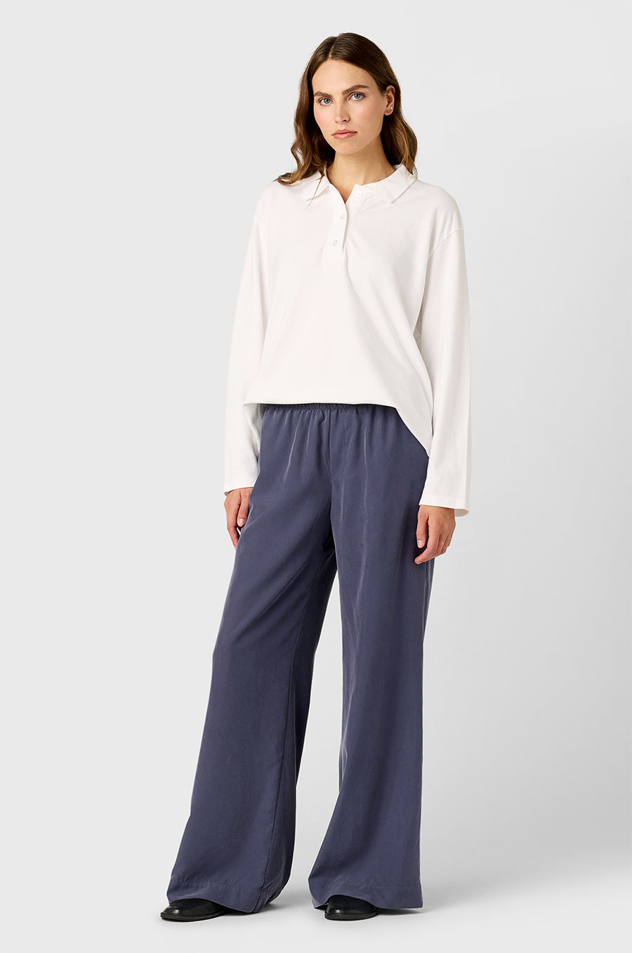 Model wearing the lady & the sailor BF Polo in White Cotton Twill and Silky Wide Leg Pants in Washed Steel.