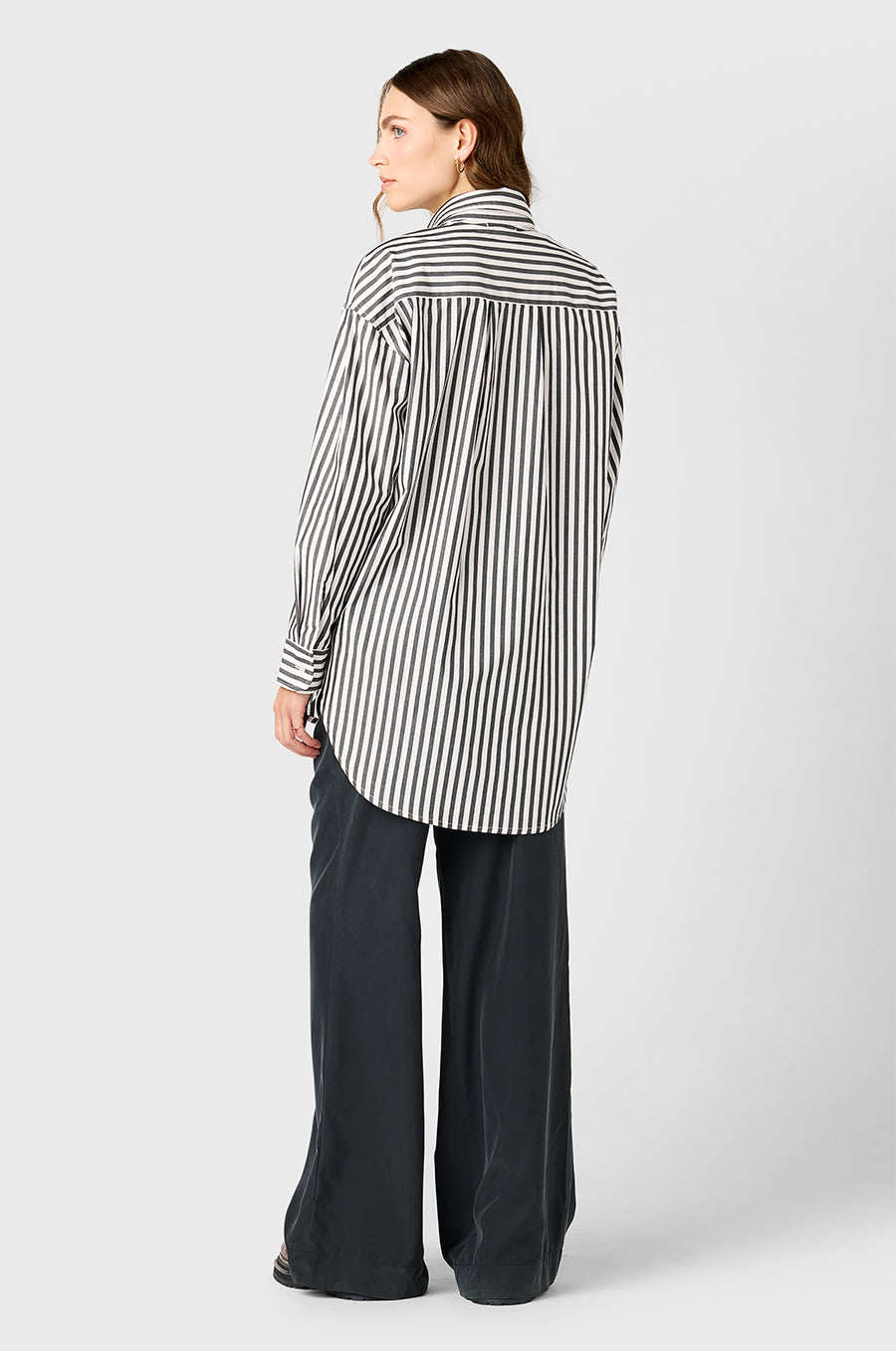 Model wearing The Lady & The Sailor Curved Hem Button up in Black/Ivory Stripe and Silky Wide Leg Pant in Washed Black.