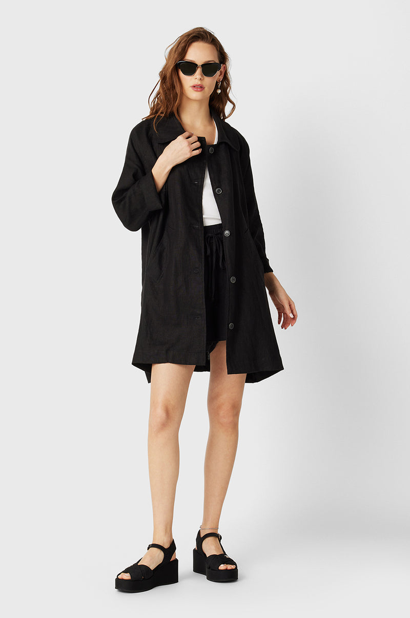 Brunette Model wearing the lady & the sailor Swing Coat in Black Linen.