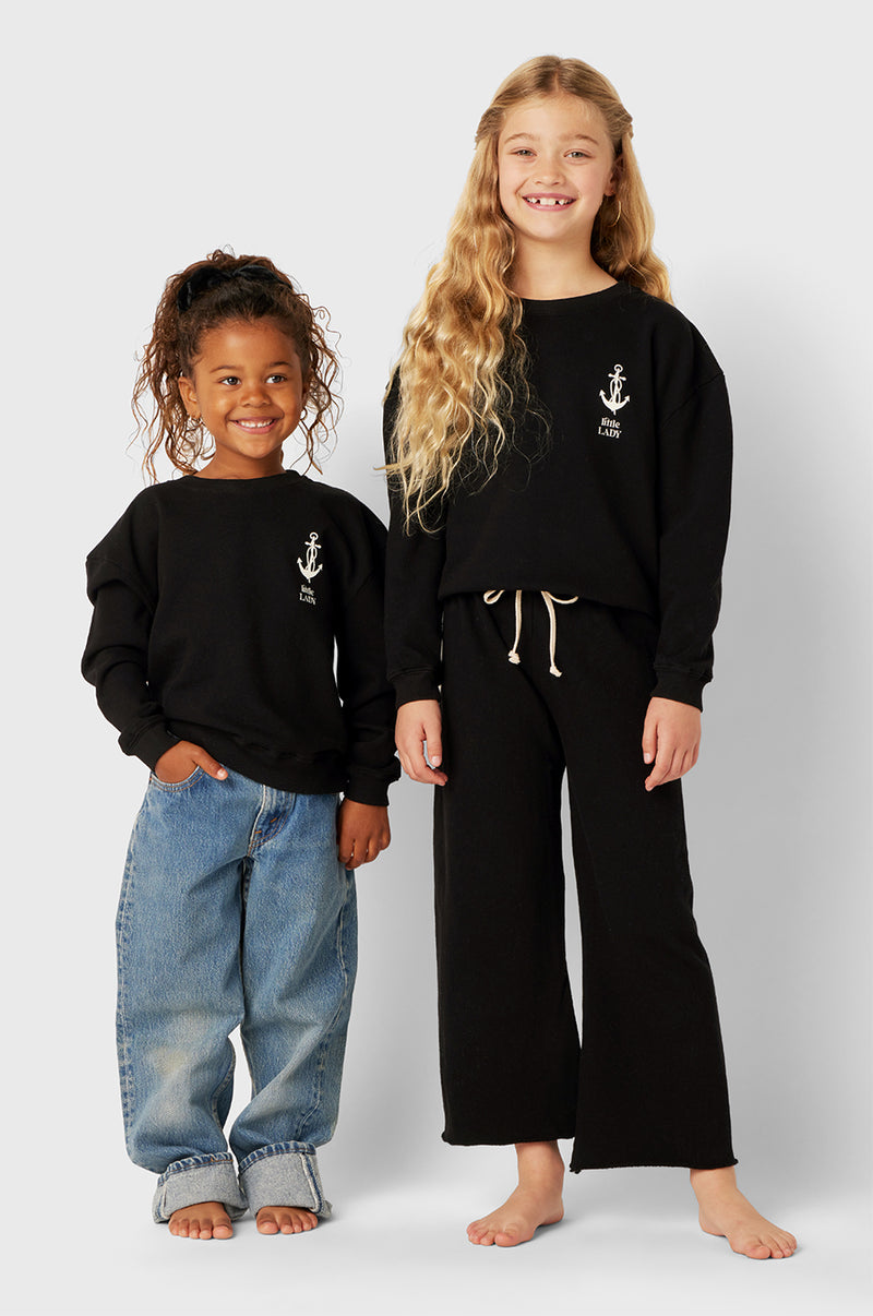 Model wearing Little Lady Varsity Crewneck in Black Organic Cotton little lady & petit sailor