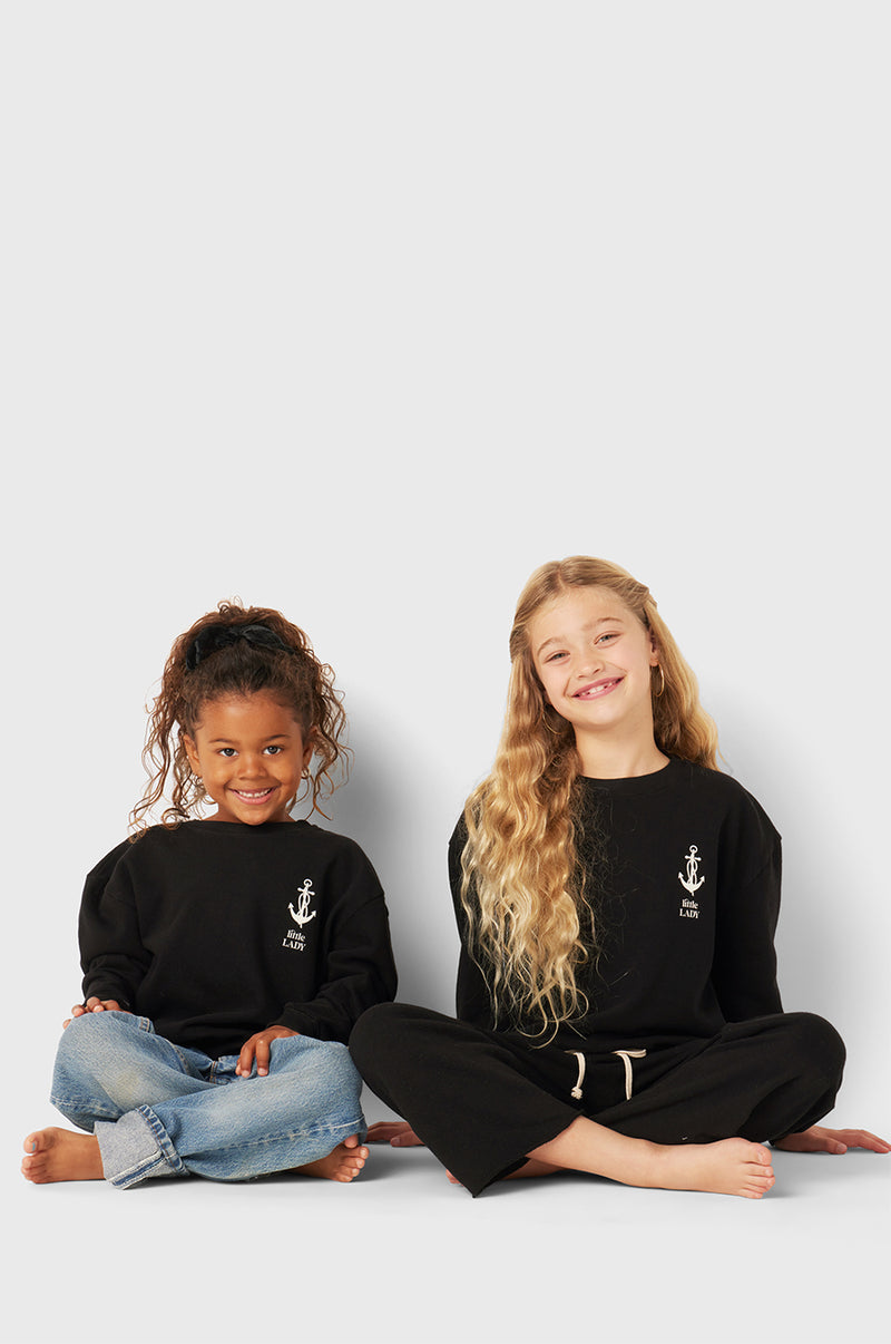 Model wearing Little Lady Varsity Crewneck in Black Organic Cotton little lady & petit sailor