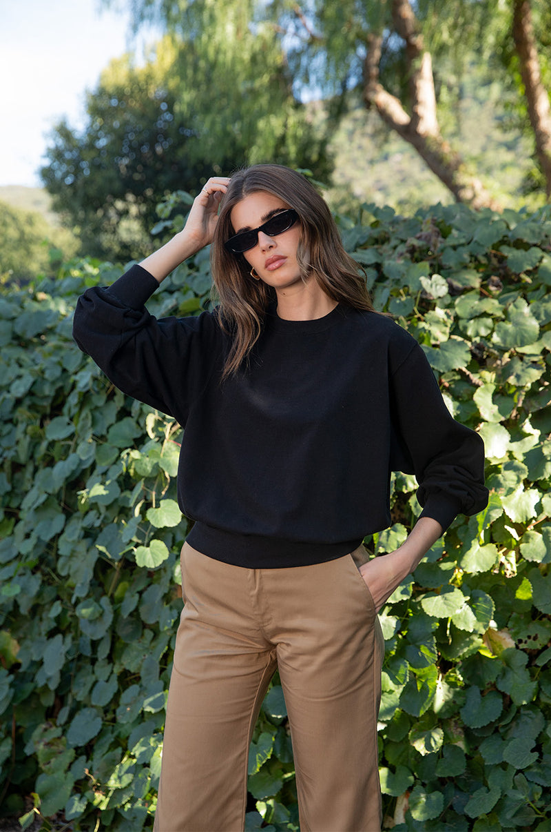 Brunette model wearing the lady & the sailor the Relaxed Sweatshirt in Black Organic Cotton.