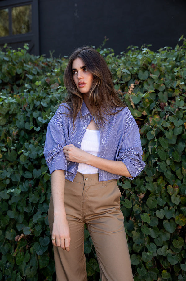 Brunette model wearing the lady & the sailor Cropped Button Up in Navy Pinstripe.