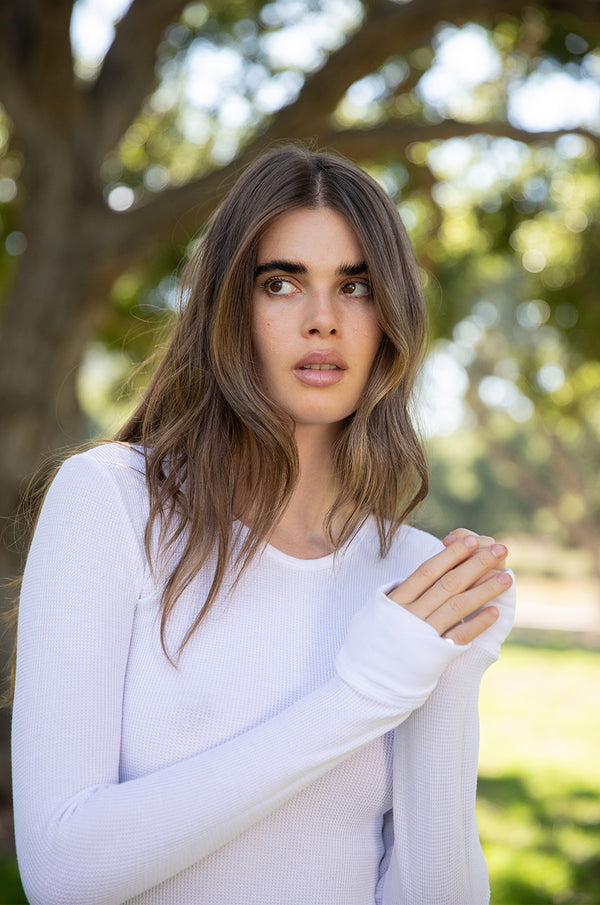 Brunette model wearing the lady & the sailor Long Sleeve Crewneck Tee in White Thermal. 