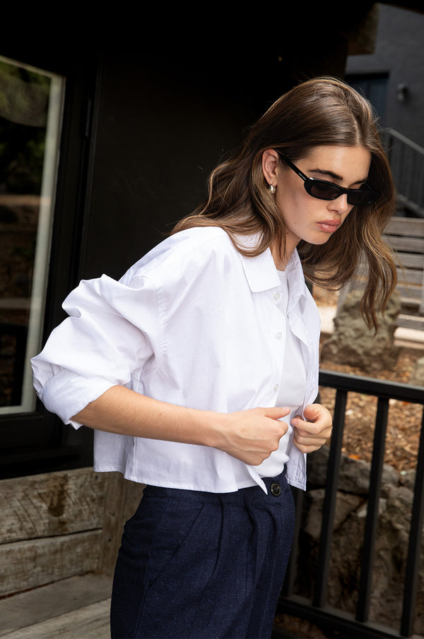 Brunette model wearing the lady & the sailor Cropped Button Up in White Poplin.