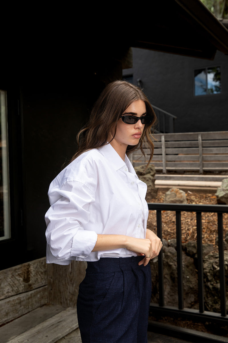 Brunette model wearing the lady & the sailor Cropped Button Up in White Poplin.