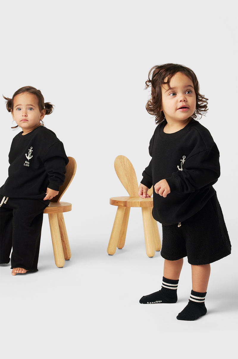 Model wearing Little Lady Varsity Crewneck in Black Organic Cotton little lady & petit sailor