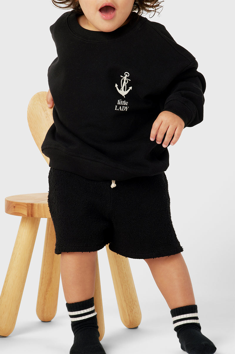 Model wearing Little Lady Varsity Crewneck in Black Organic Cotton little lady & petit sailor