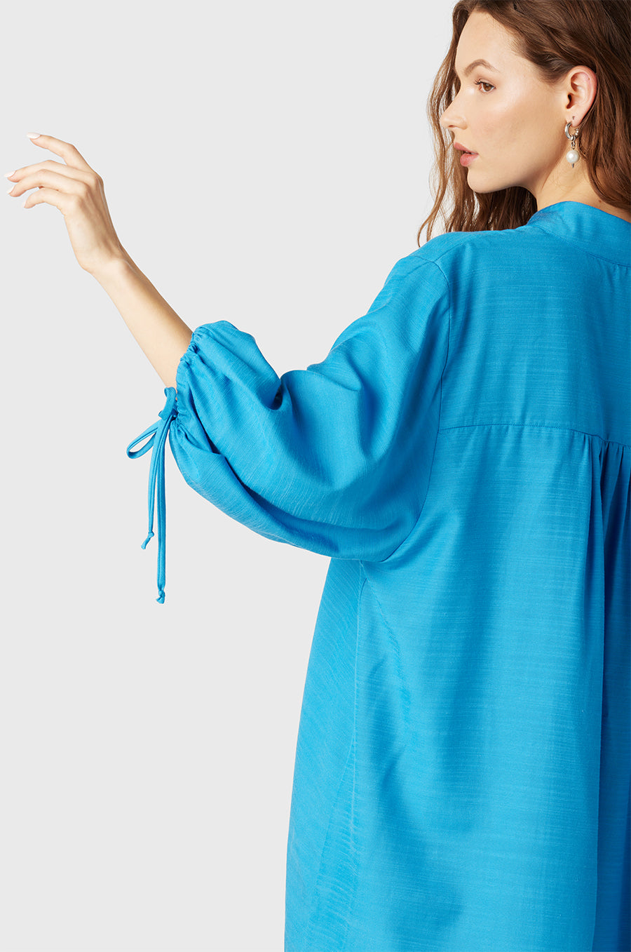 Brunette Model wearing the lady & the sailor Billow Sleeve Mini Dress in Turquoise.