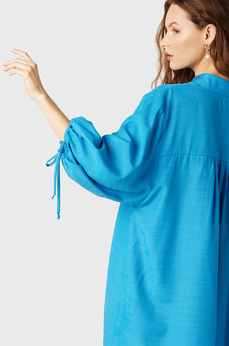 Brunette Model wearing the lady & the sailor Billow Sleeve Mini Dress in Turquoise.