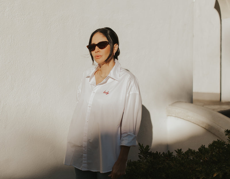 Brunette Model wearing the lady & the sailor Lady Button Up in White Cotton Poplin/Ruby.