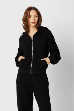 Brunette Model wearing the lady & the sailor the Zip Up Hoodie in Black Boucle.