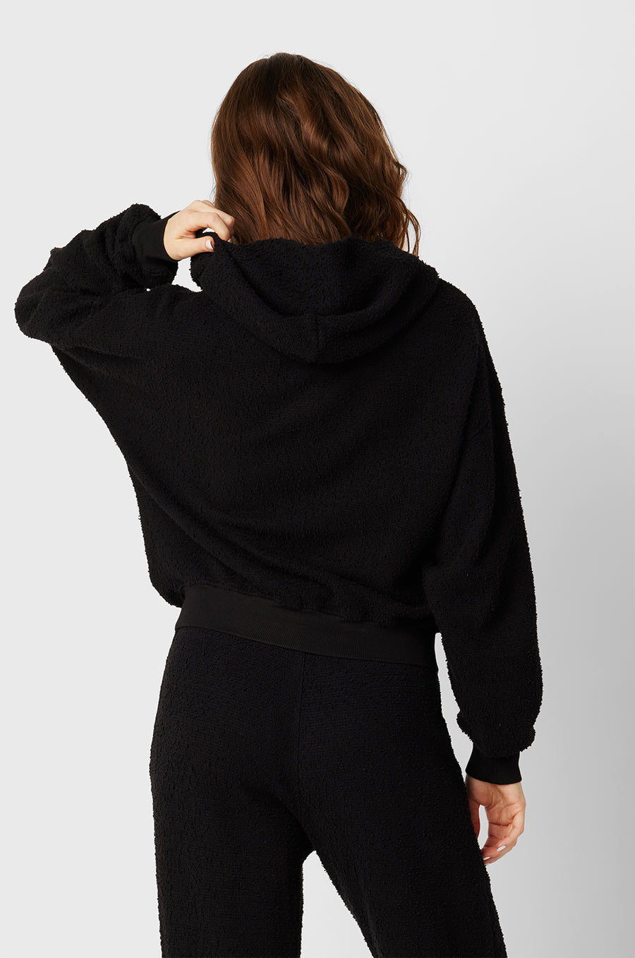 Brunette Model wearing the lady & the sailor the Zip Up Hoodie in Black Boucle.