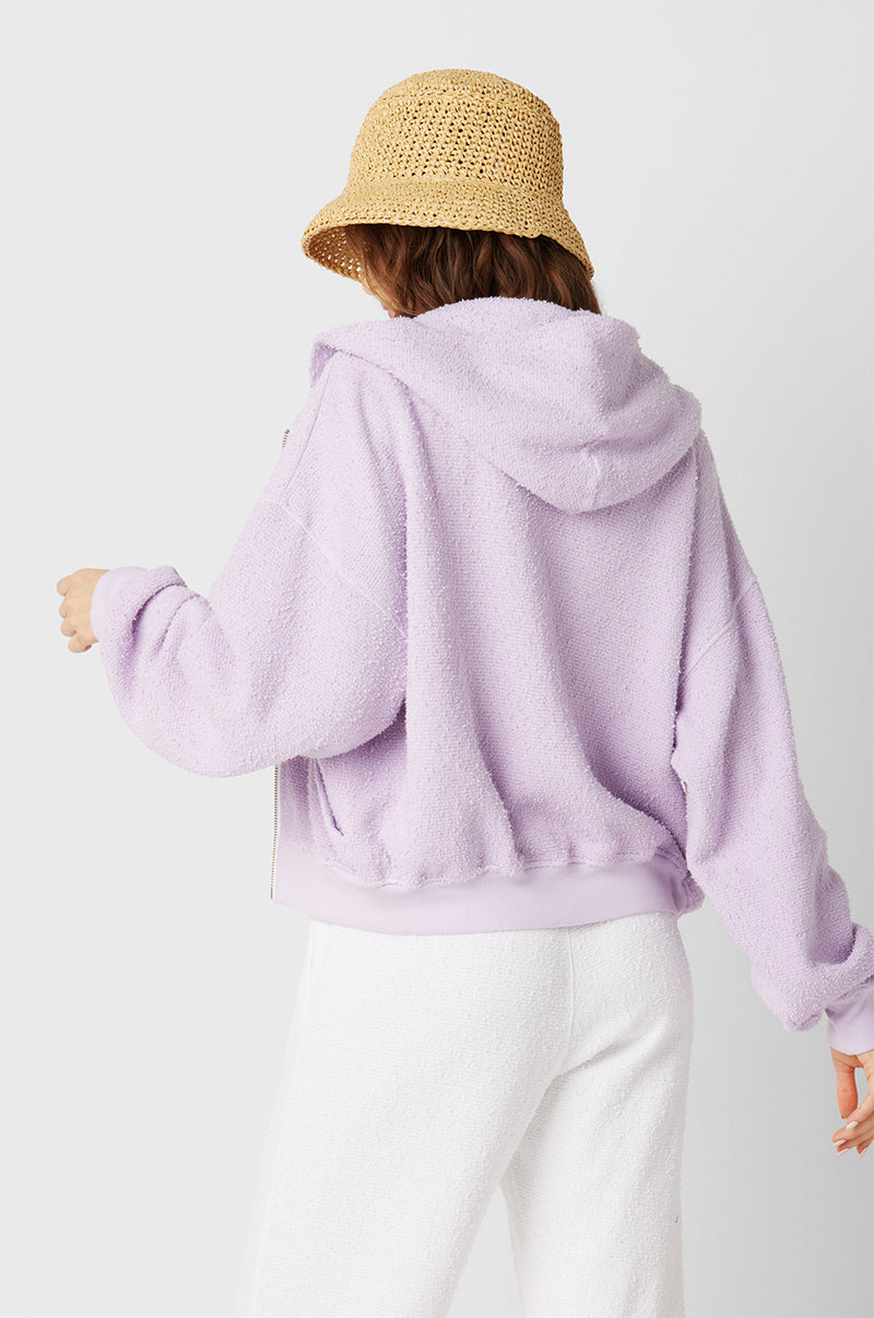 Brunette Model wearing the lady & the sailor the Zip Up Hoodie in Lilac Boucle.