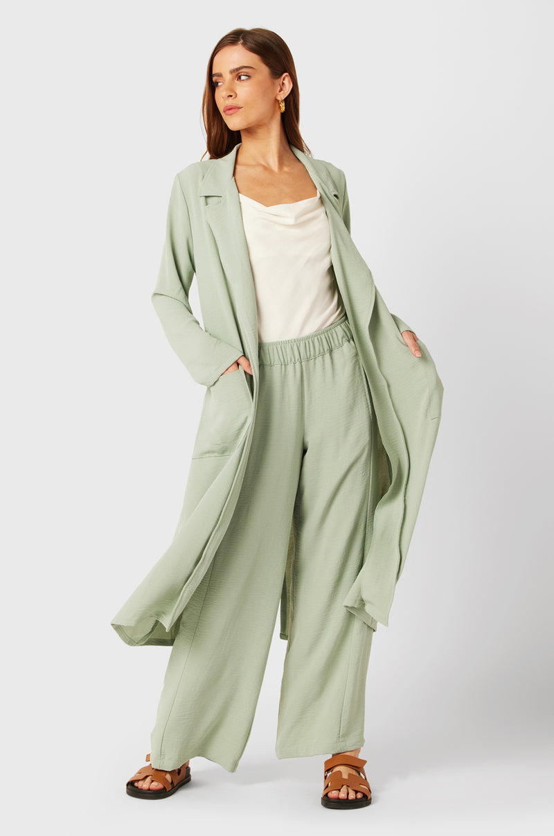 Brunette Model wearing the lady & the sailor Belted Coat in Seaglass Air Flow.