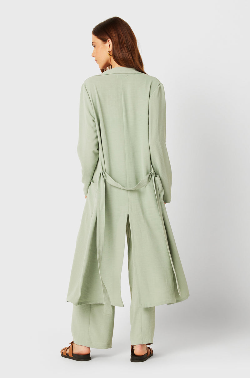 Brunette Model wearing the lady & the sailor Belted Coat in Seaglass Air Flow.