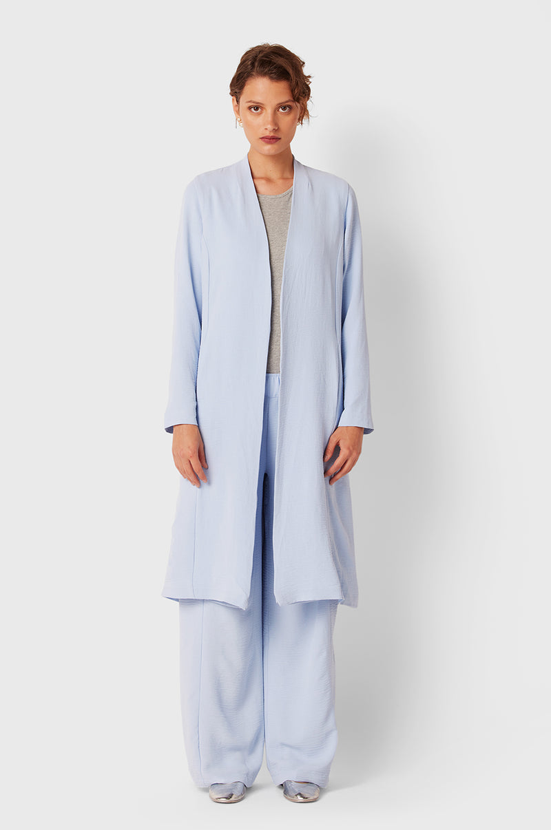 Brunette Model wearing the lady & the sailor Midi Duster Coat in Glacier Air Flow.
