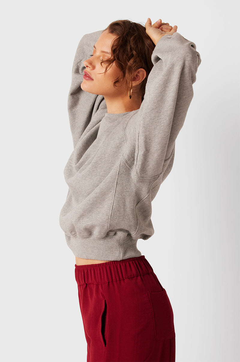 Brunette Model wearing the lady & the sailor The Kristin Sweatshirt in Heather Grey Fleece.