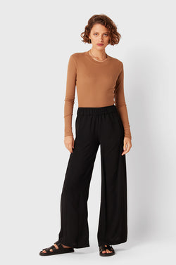 Brunette Model wearing the lady & the sailor Palazzo Pant in Black Air Flow.