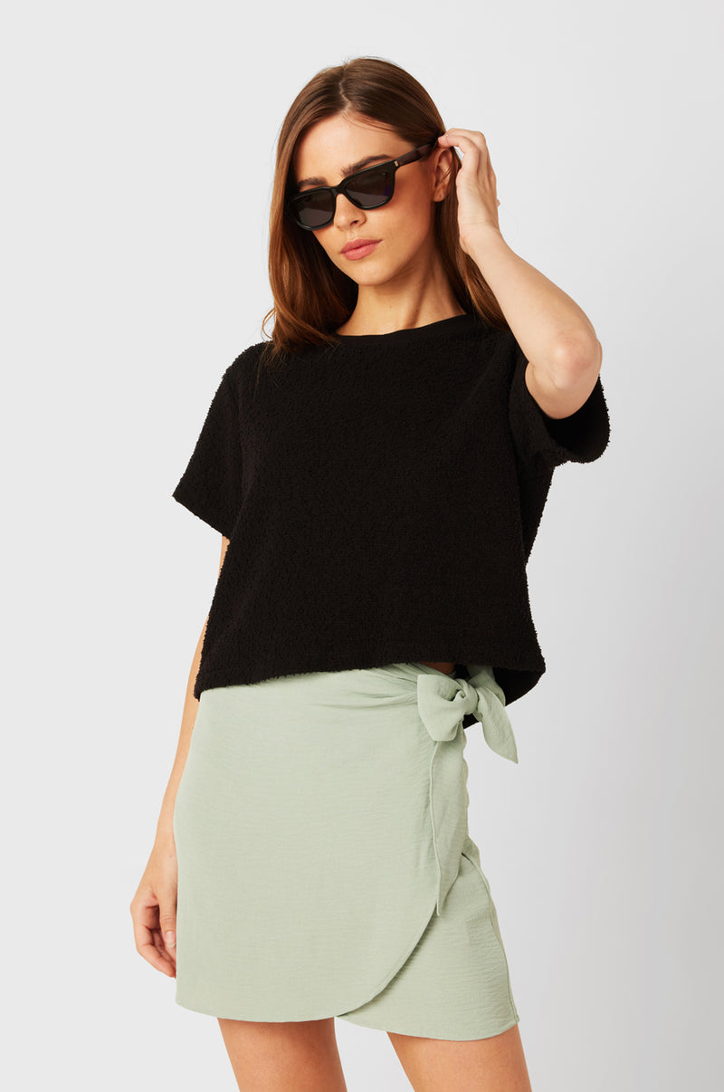 Brunette Model wearing the lady & the sailor Wrap Mini Skirt in Seaglass Air Flow.