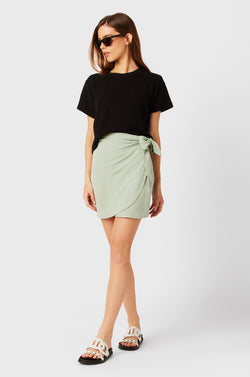 Brunette Model wearing the lady & the sailor Wrap Mini Skirt in Seaglass Air Flow.