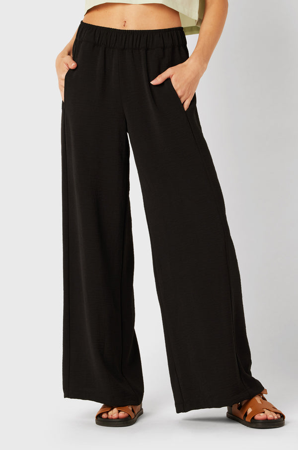 Brunette Model wearing the lady & the sailor Palazzo Pant in Black Air Flow.