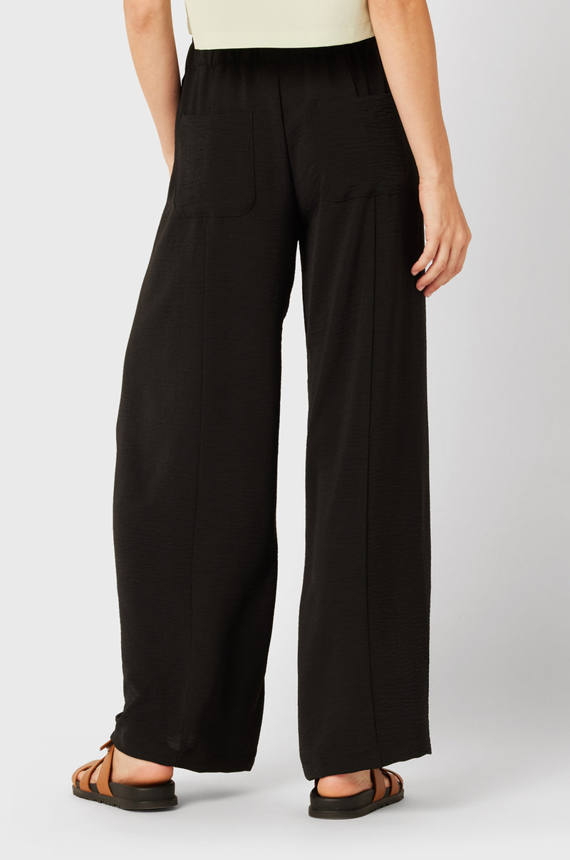 Brunette Model wearing the lady & the sailor Palazzo Pant in Black Air Flow.