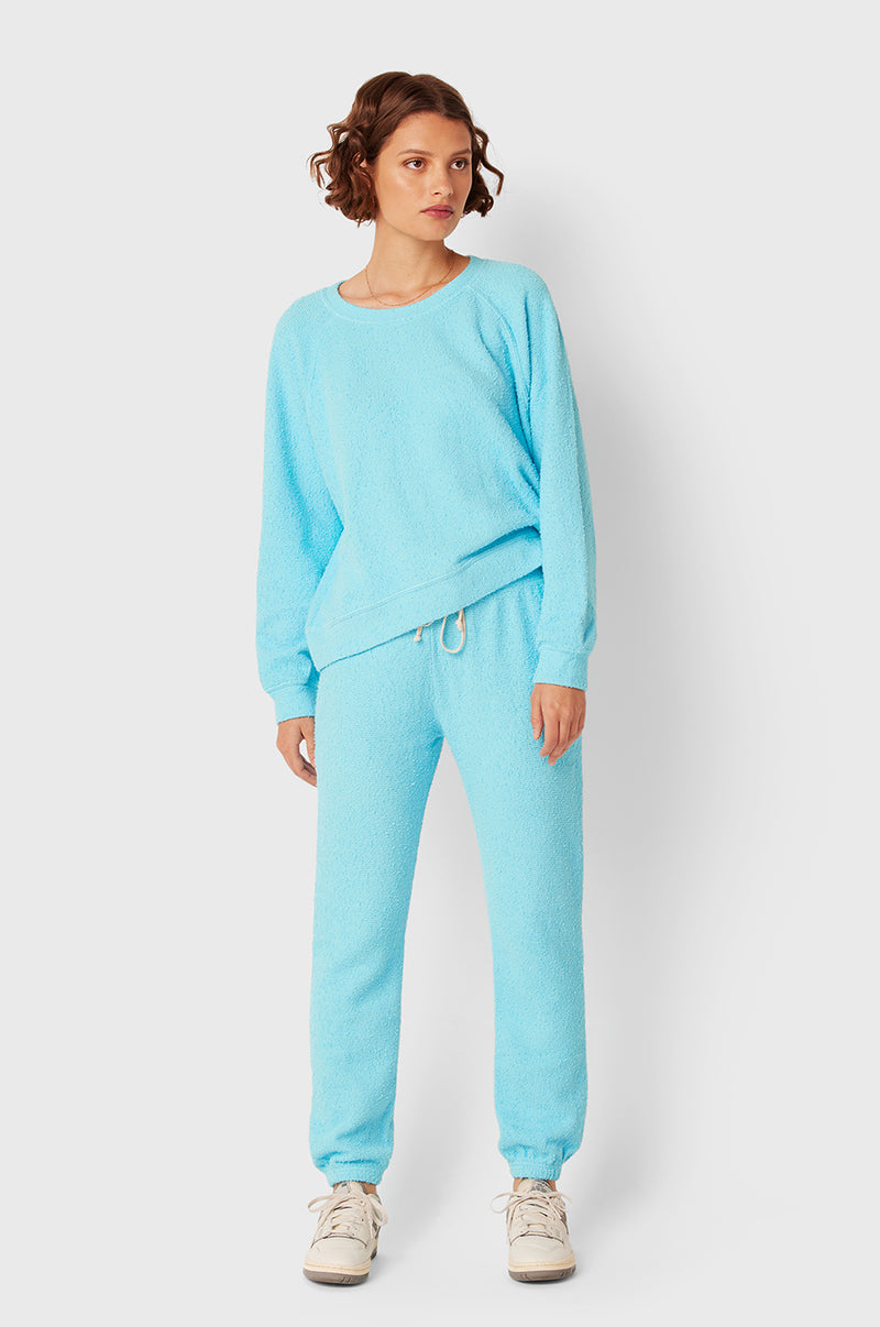 Brunette Model wearing the lady & the sailor Full Length Vintage Sweatpant in Turquoise Bouclé.