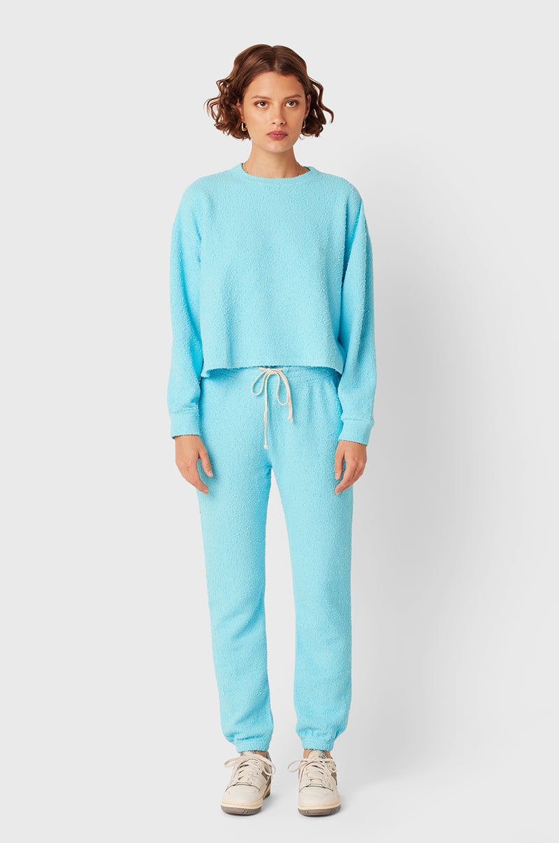 Brunette Model wearing the lady & the sailor Full Length Vintage Sweatpant in Turquoise Bouclé.